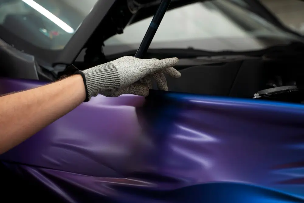Automotive service salon applying paint protection film during car wrapping in Dubai.